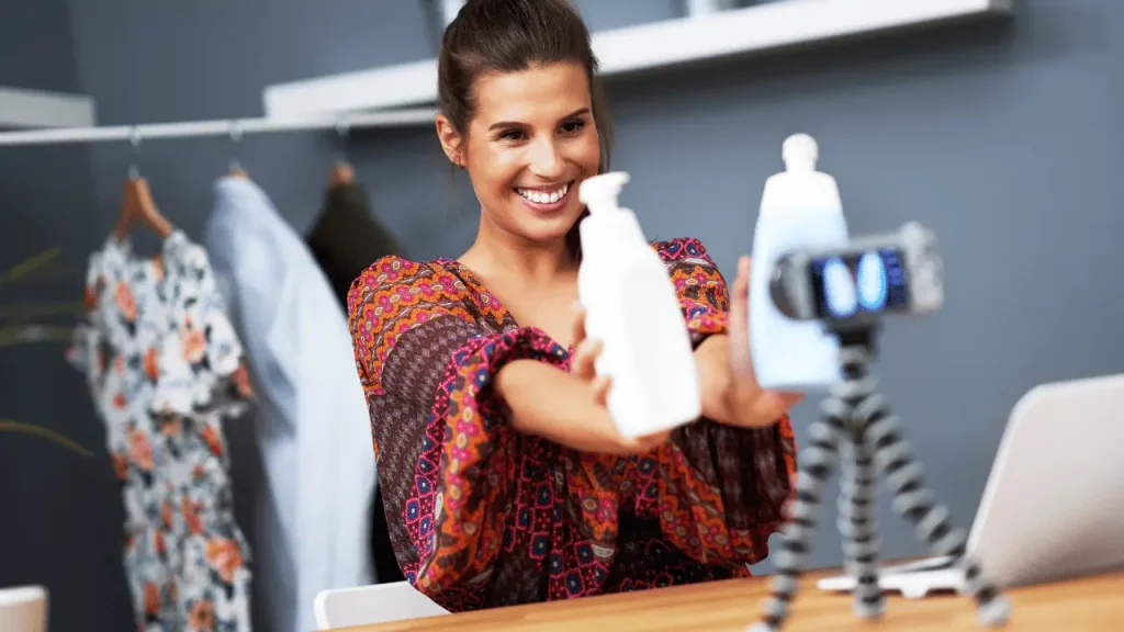 Influenciadora digital sorrindo e mostrando dois produtos para a câmera.