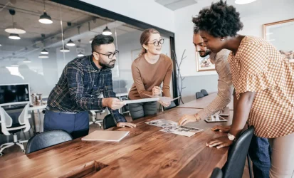 Pessoas em volta de uma mesa, em um ambiente empresarial. São dois homens e duas mulhers.