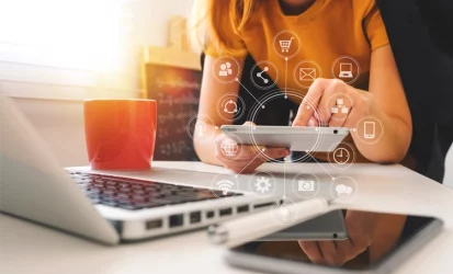 Mulher em frente a um notebook e teclando um tablet com ícones tecnológicos translúcidos.